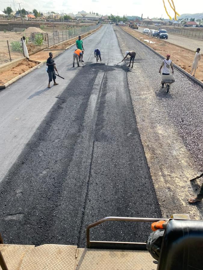 Crew hand-levelling asphalt behind the paver